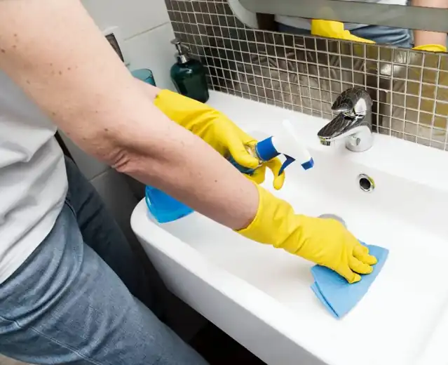 Professional cleaner wiping and sanitizing a bathroom sink in London Ontario