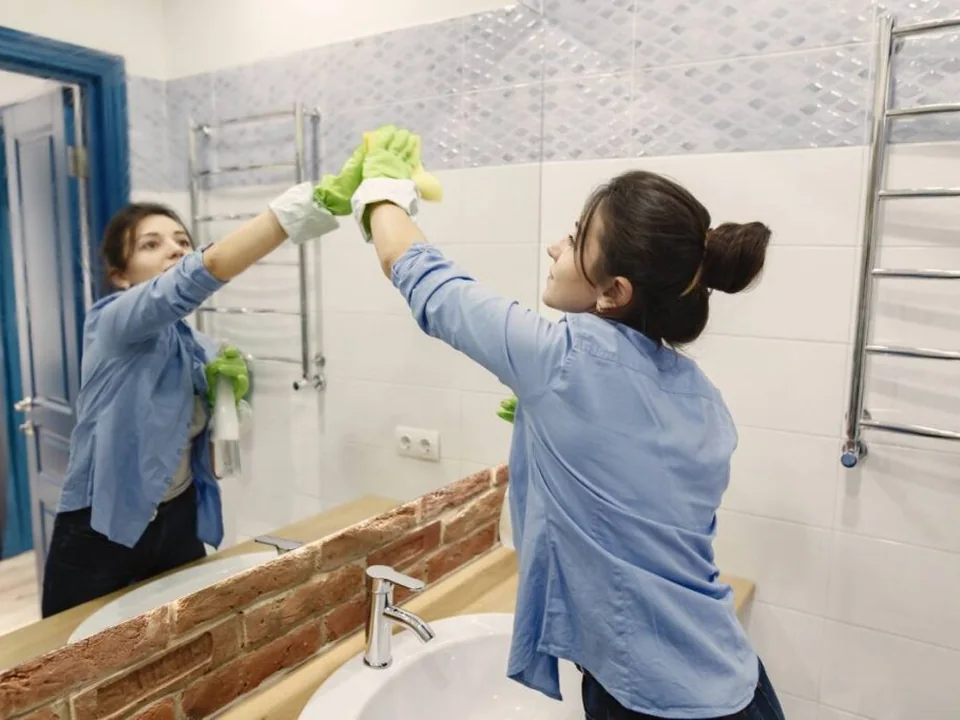 Professional cleaner carefully cleaning a bathroom mirror